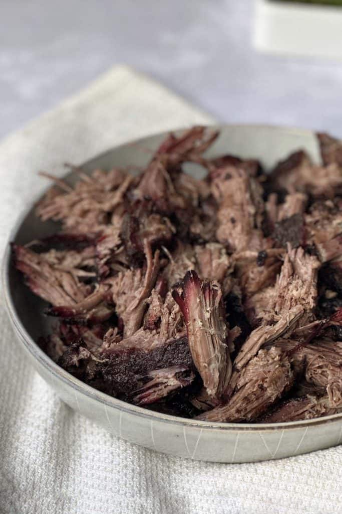 Mouth watering pulled smoked chuck roast in a off white bowl.